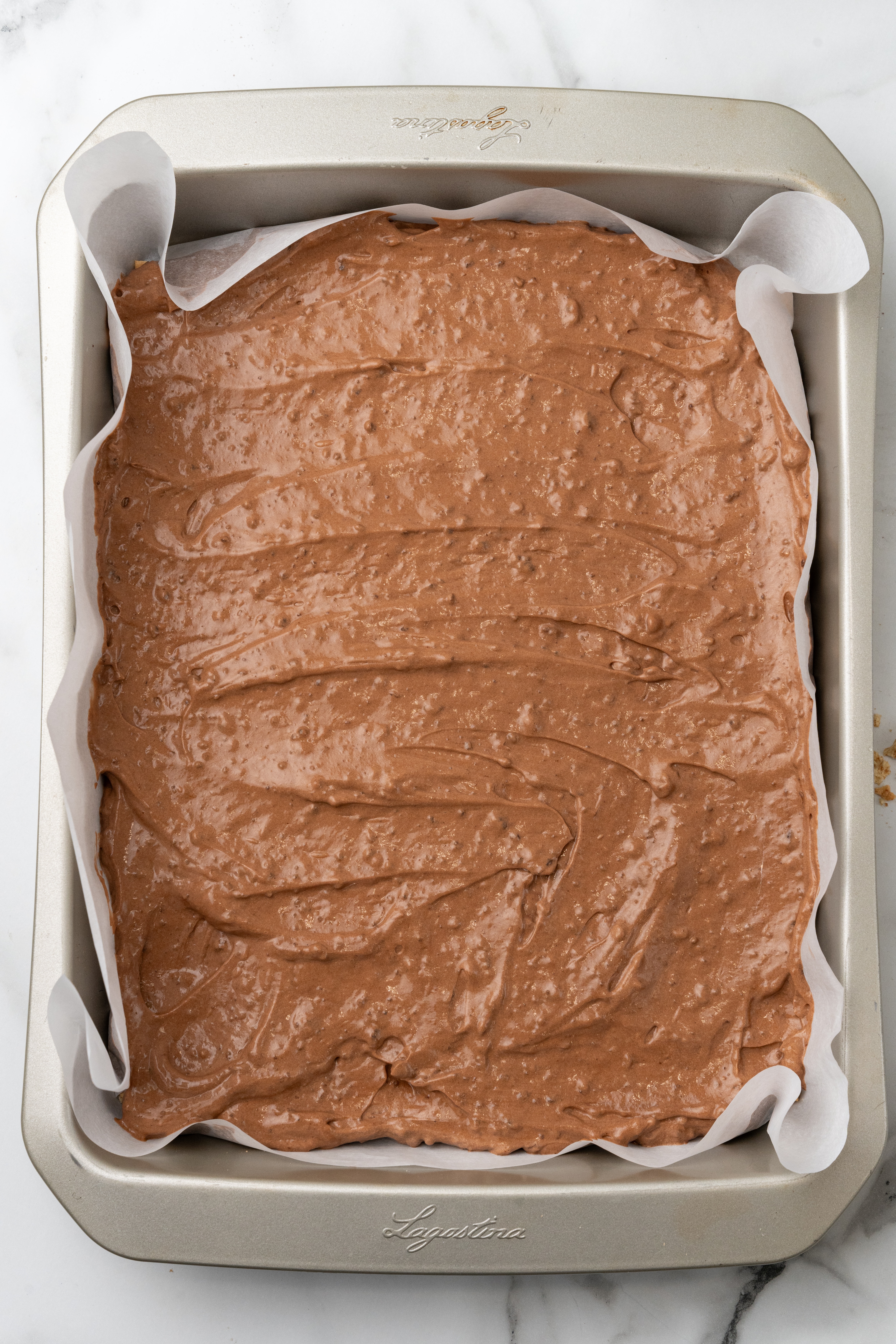 creamy chocolate pudding spread over graham crackers in a parchment paper lined baking pan