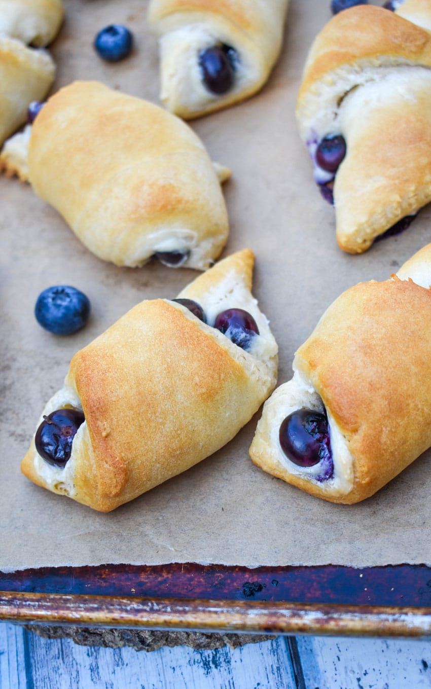 blueberry cream cheese crescent rolls on a parchment paper lined baking sheet