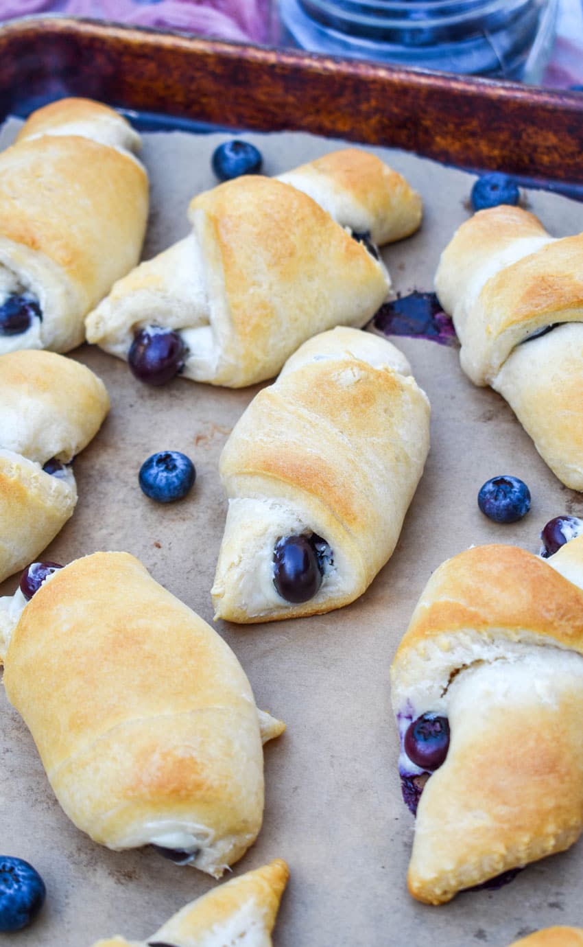 blueberry cream cheese crescent rolls on a parchment paper lined baking sheet