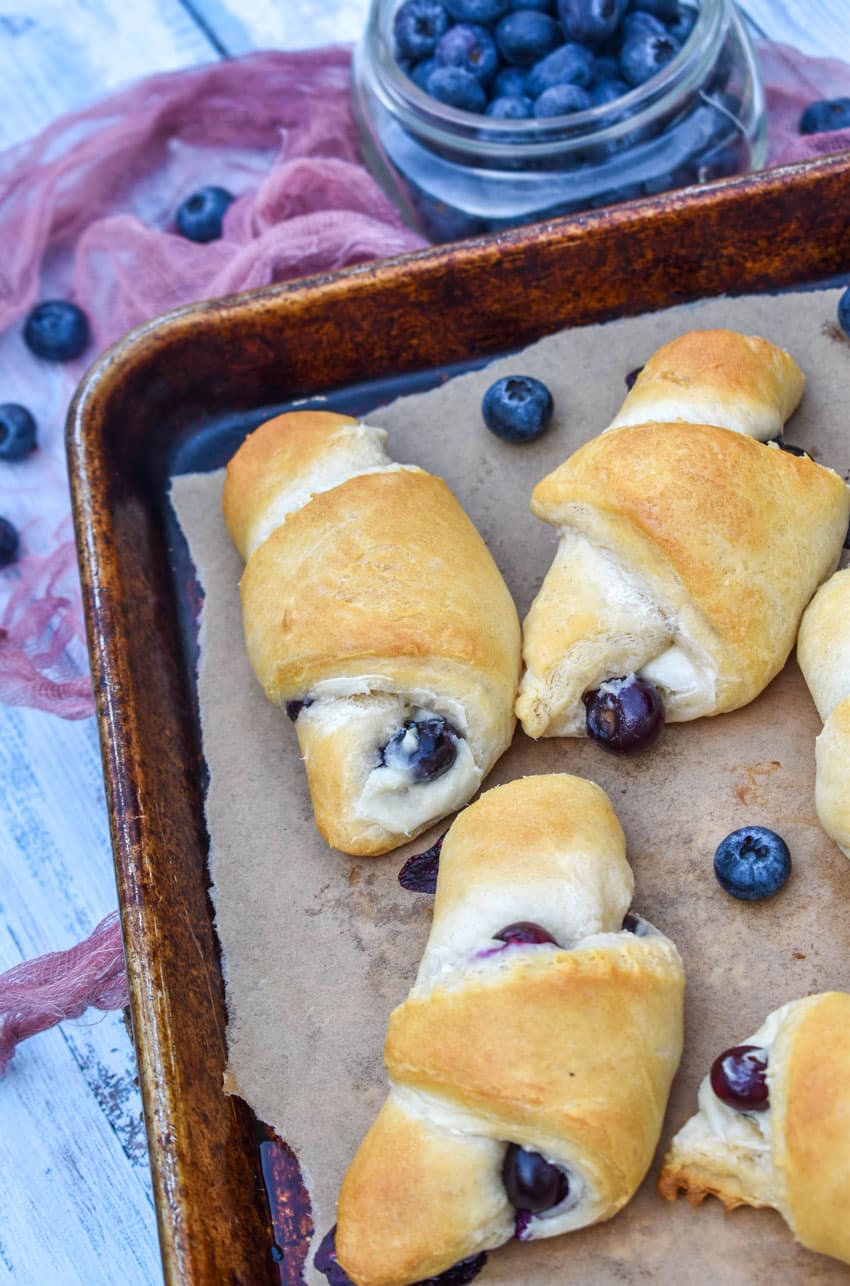 blueberry cream cheese crescent rolls on a parchment paper lined baking sheet