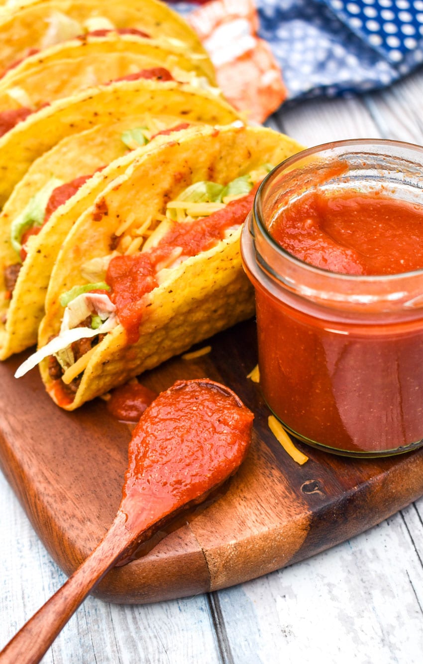 a wooden spoon filled with copy cat taco bell mild sauce resting on a wooden cutting board