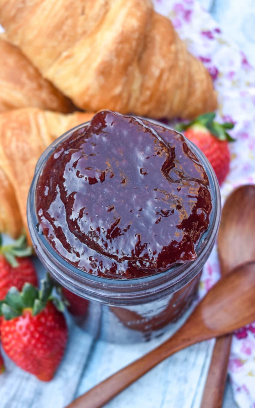 strawberry jam recipe without pectin in a glass jar with croissant rolls on the side