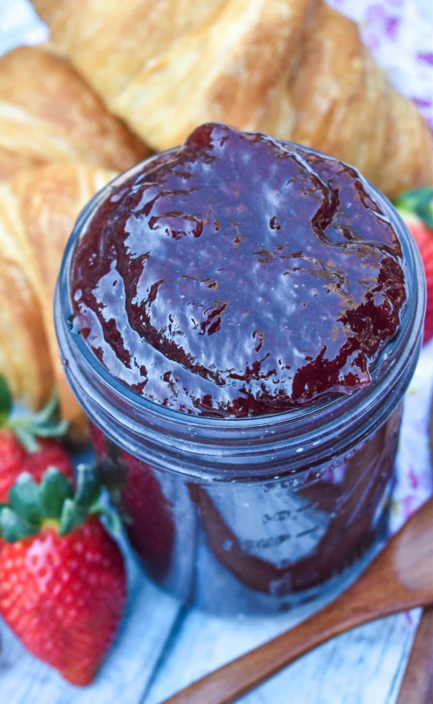 strawberry jam recipe without pectin in a glass jar with croissant rolls on the side