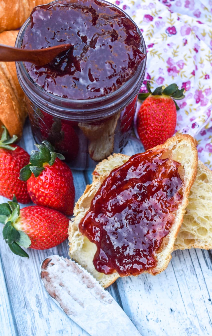 a strawberry jam recipe without pectin spread on a halved croissant roll surrounded by fresh strawberries