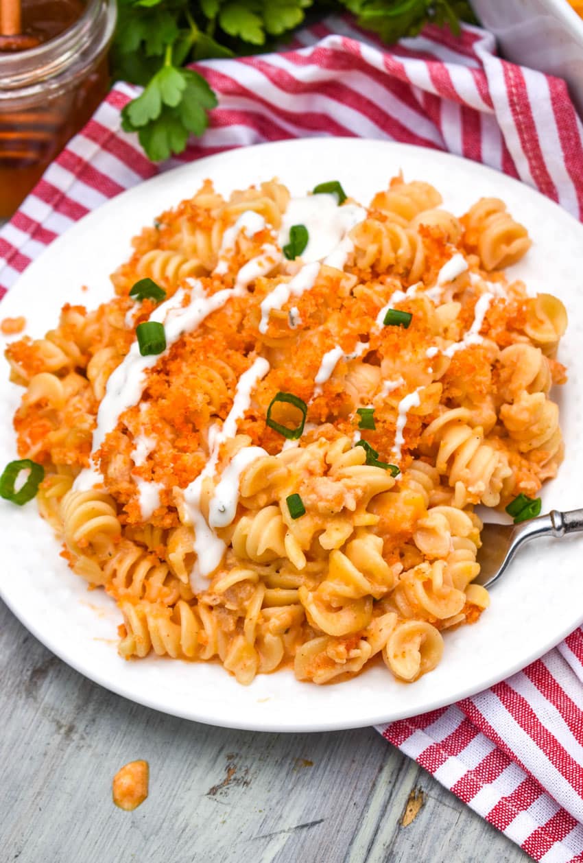 a silver fork digging into a serving of cheesy nashville hot chicken casserole on a white plate