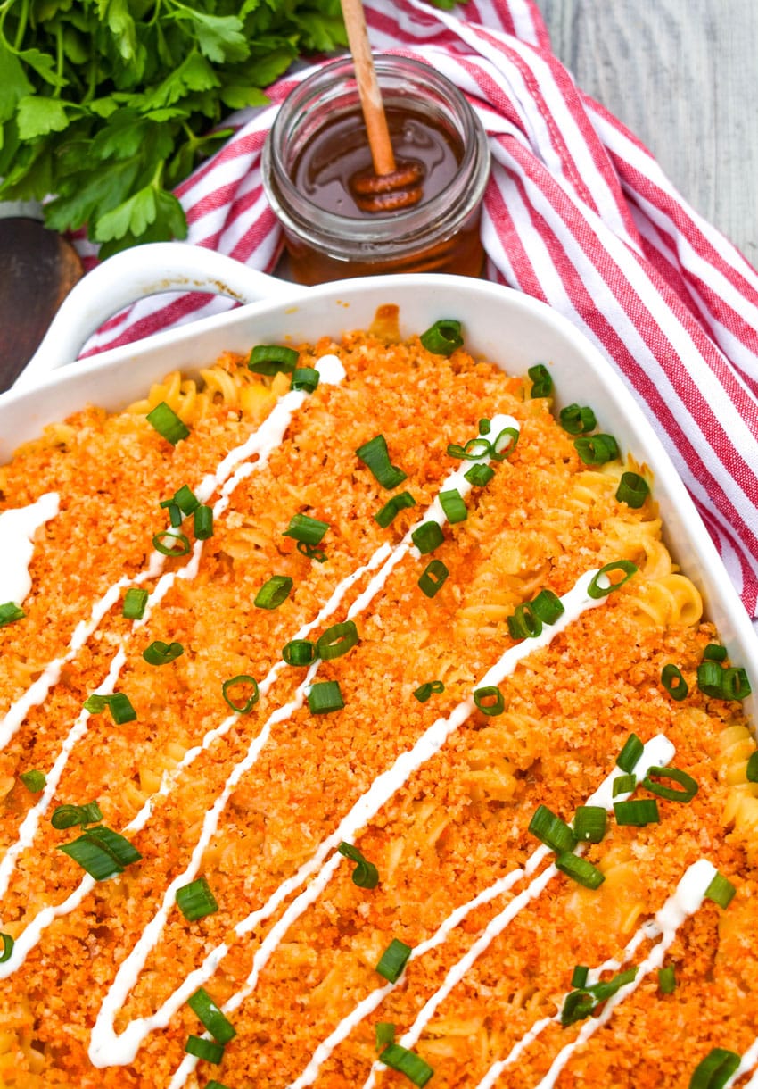 nashville hot chicken casserole topped with a drizzle of ranch dressing and sliced green onions in a white baking dish