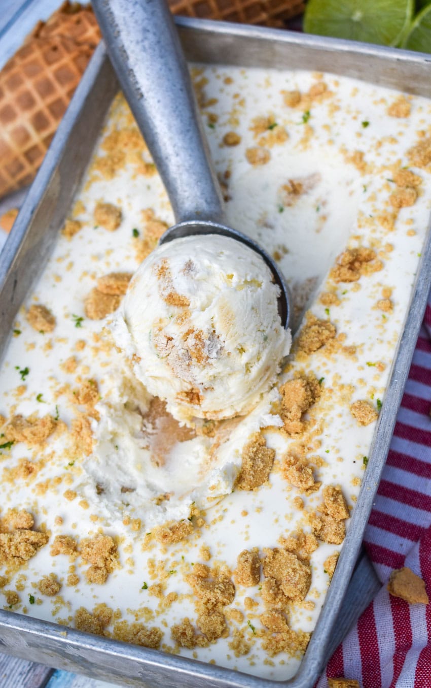 a metal ice cream scoop scooping no churn key lime pie ice cream out of a metal loaf pan