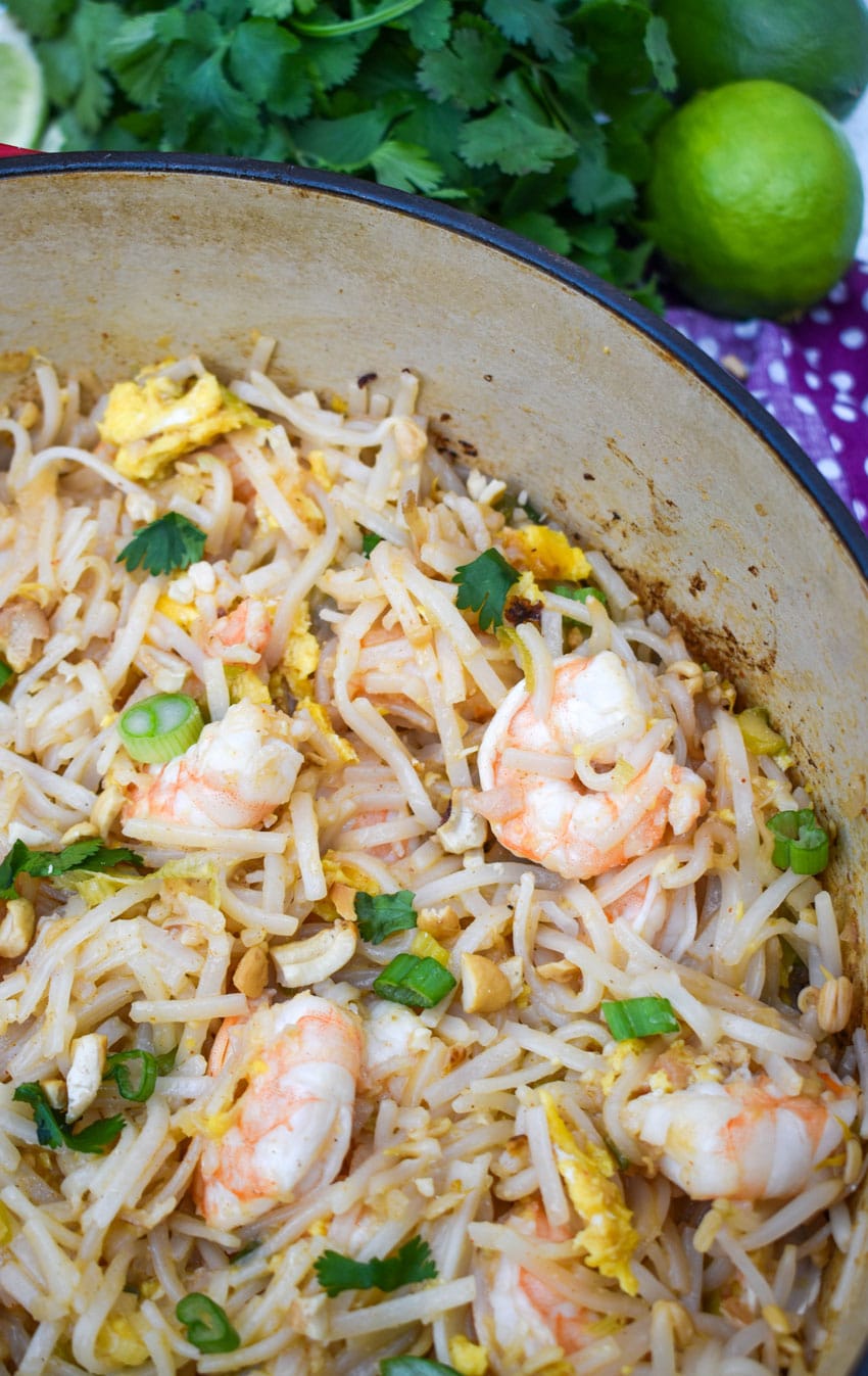 shrimp pad thai noodles in a red dutch oven with fresh cilantro in the background