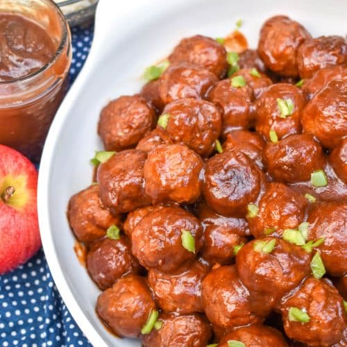 apple butter meatballs sprinkled with diced green peppers in a white serving bowl