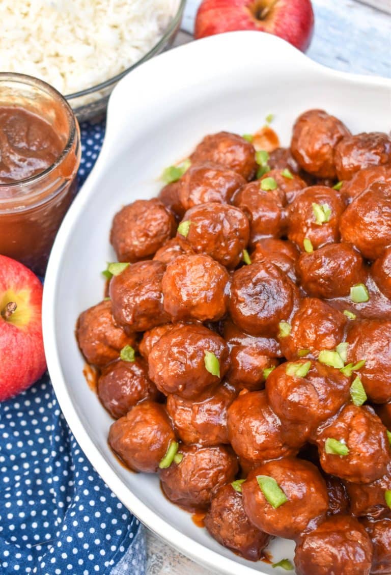 apple butter meatballs sprinkled with diced green peppers in a white serving bowl