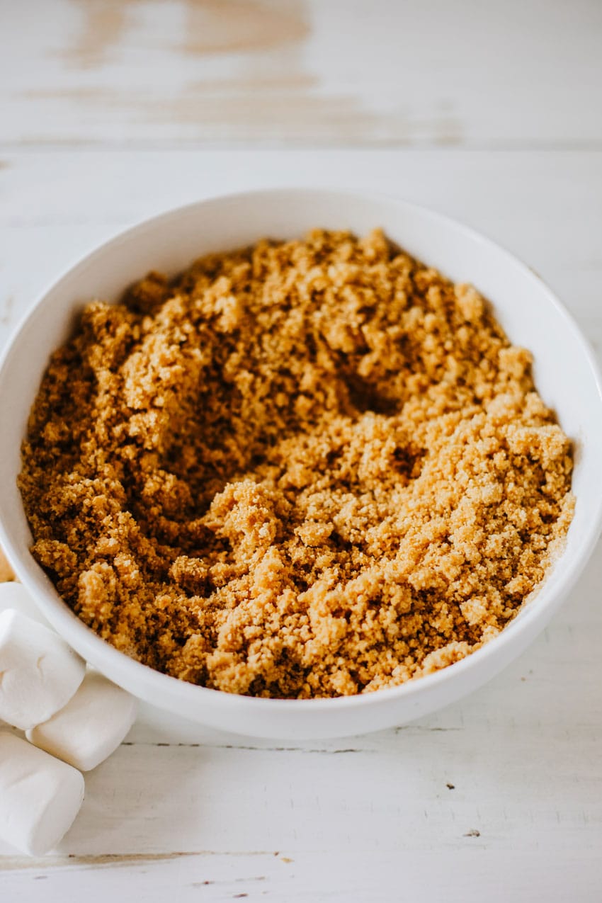 seasoned graham cracker crumbs mixed with butter in a small white bowl