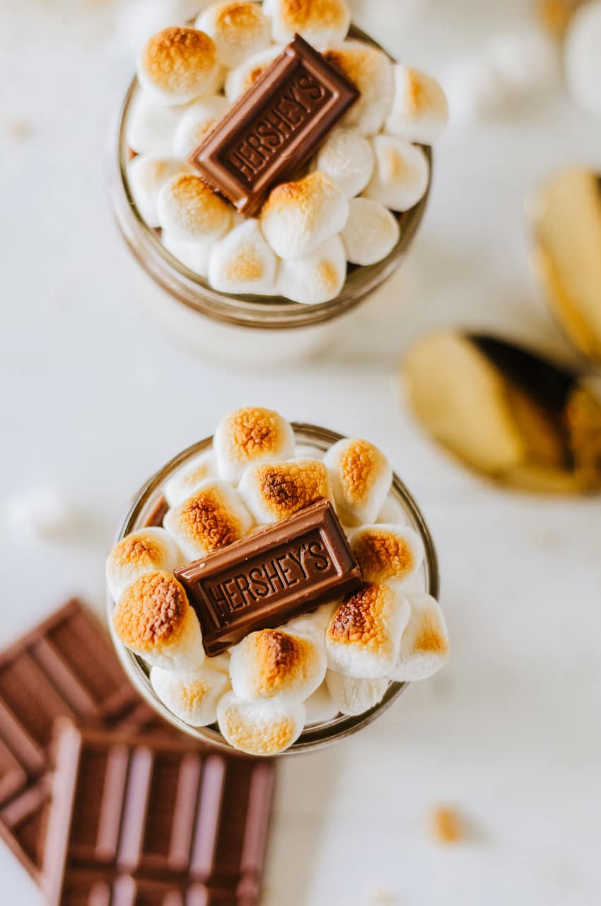 two s'mores trifles in small glass jars on a wooden table