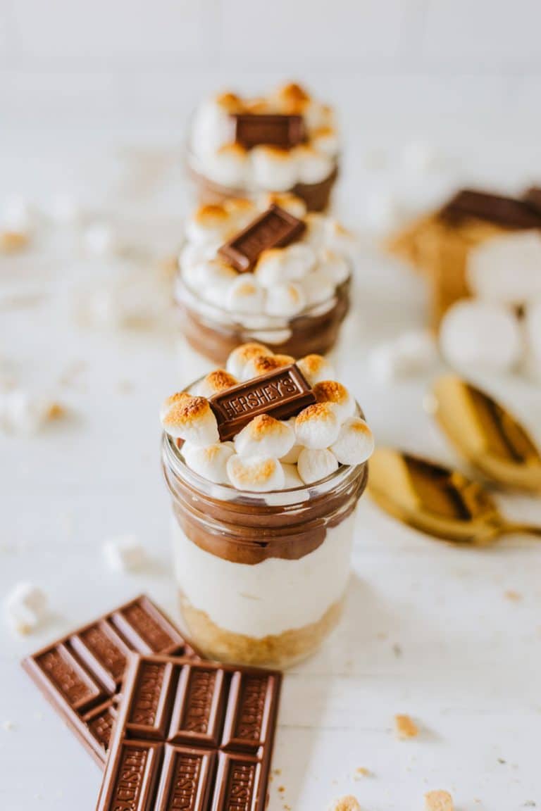 three s'mores trifles in small glass jars on a wooden table