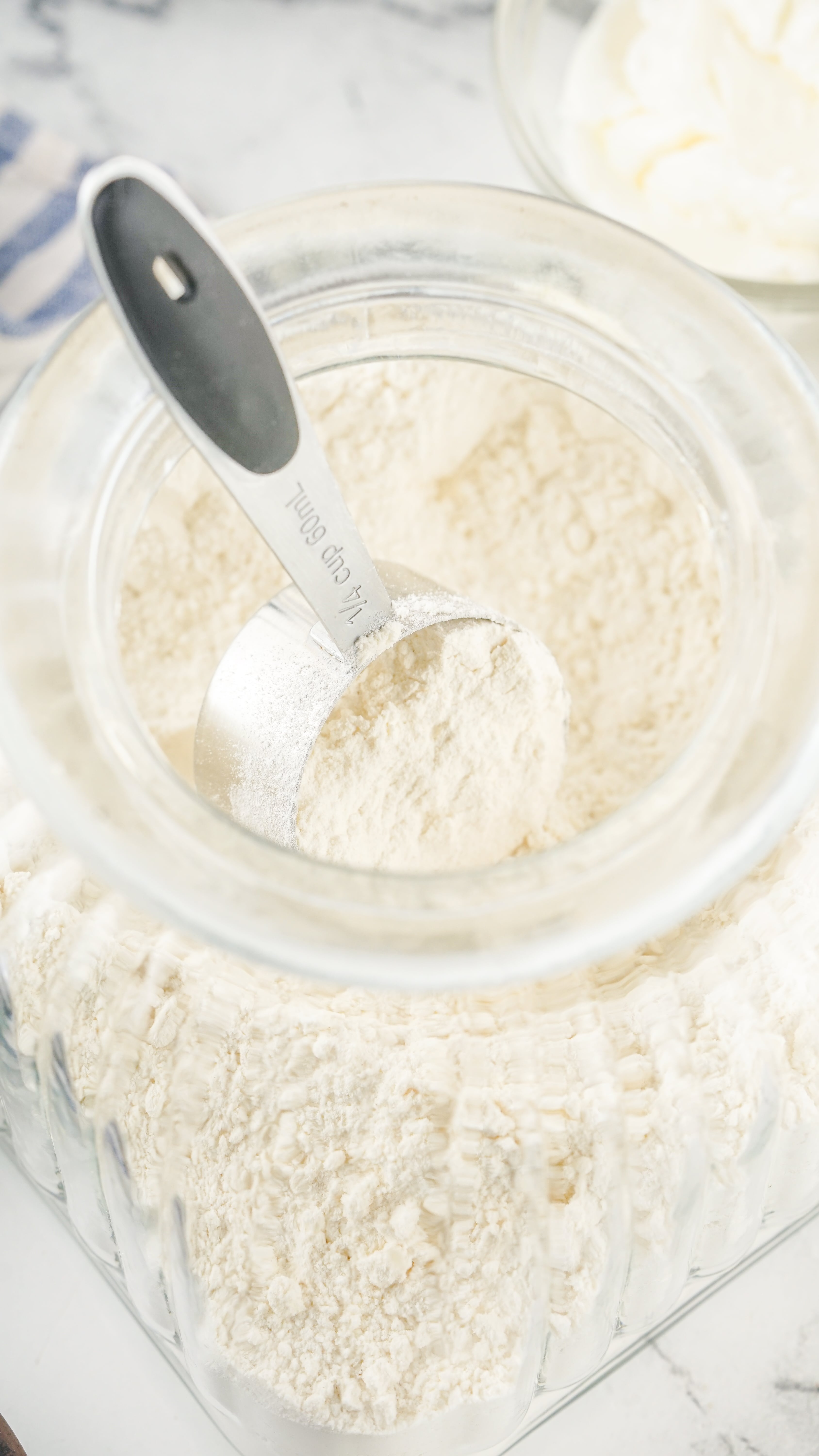 a metal measuring cup scooping homemade bisquick out of a glass jar