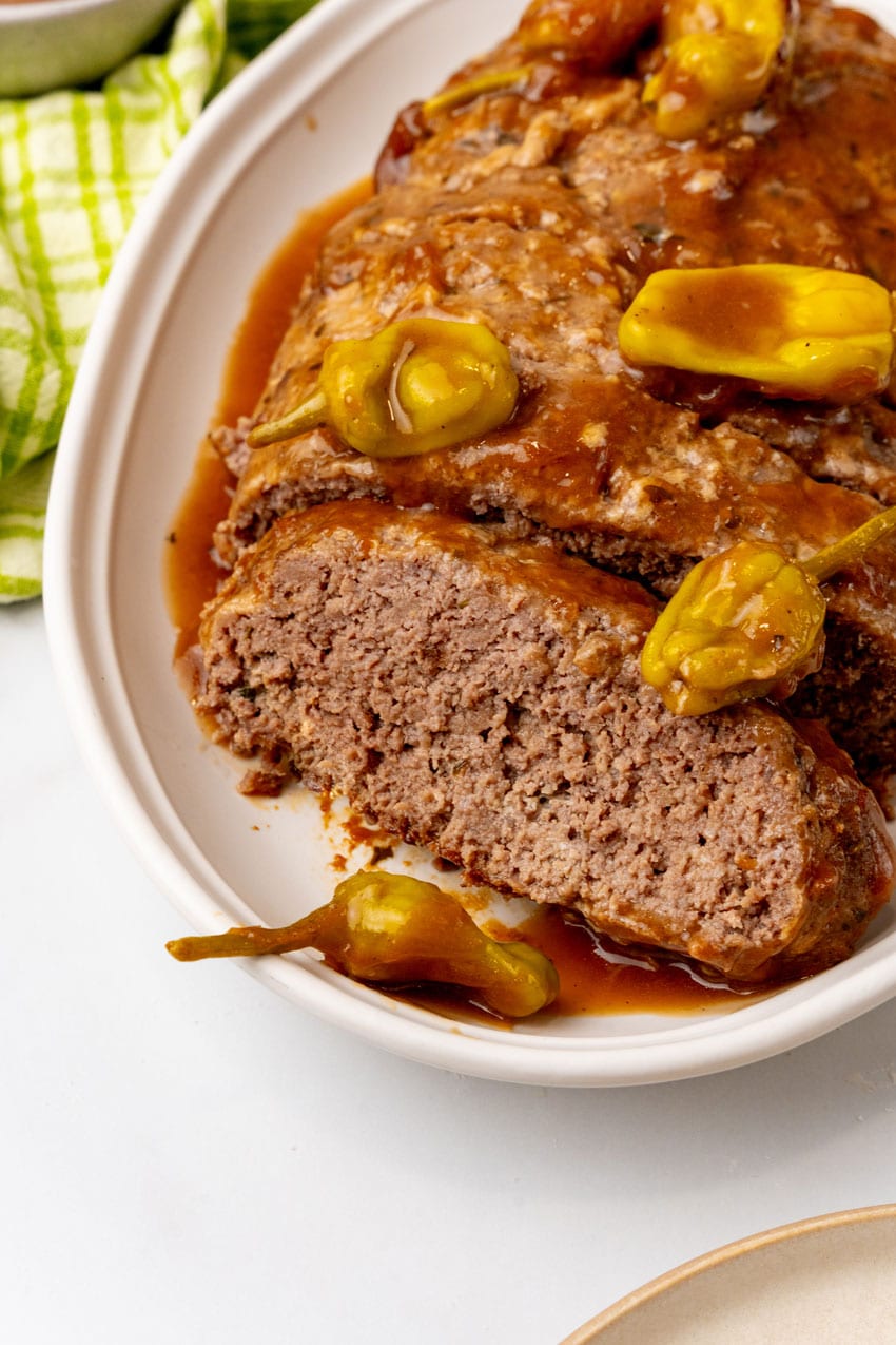 a sliced mississippi meatloaf with gravy on a white serving platter