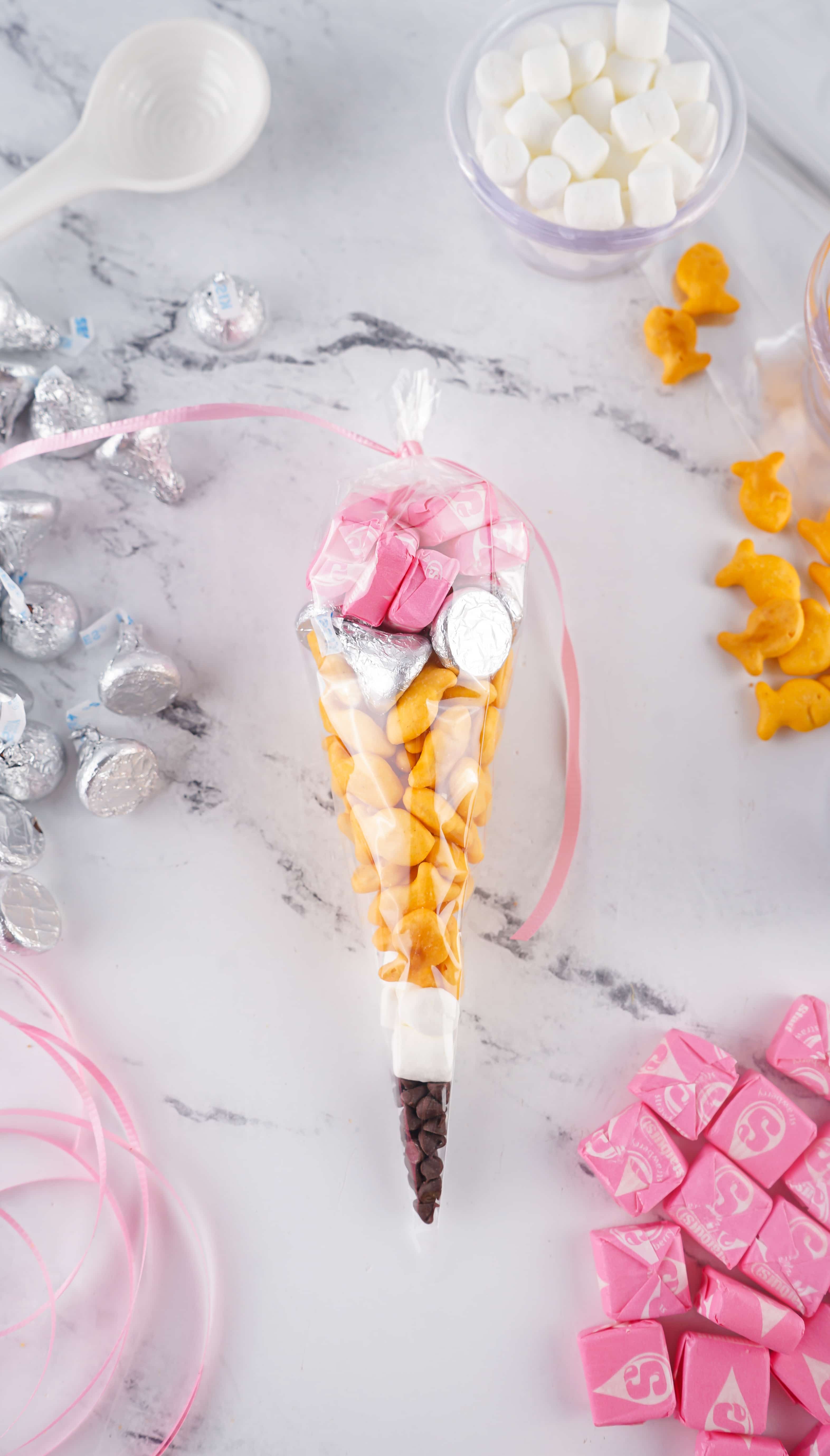 a back to school pencil treat bag tied with pink ribbon laying on a marble counter top