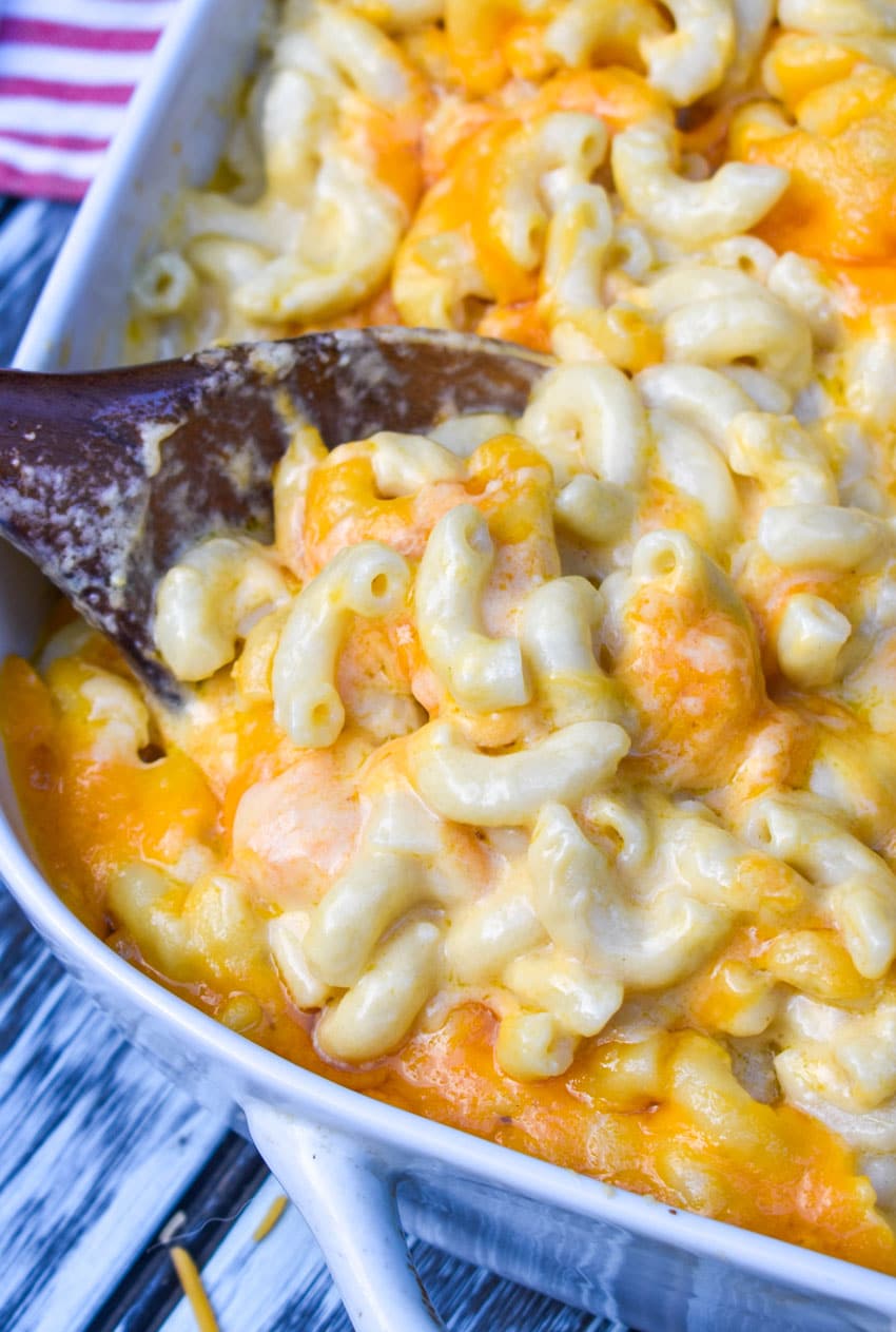 a wooden spoon scooping copycat chick fil a mac and cheese out of white baking dish