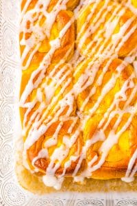 a closeup of pumpkin danish hawaiian rolls drizzle with white glaze