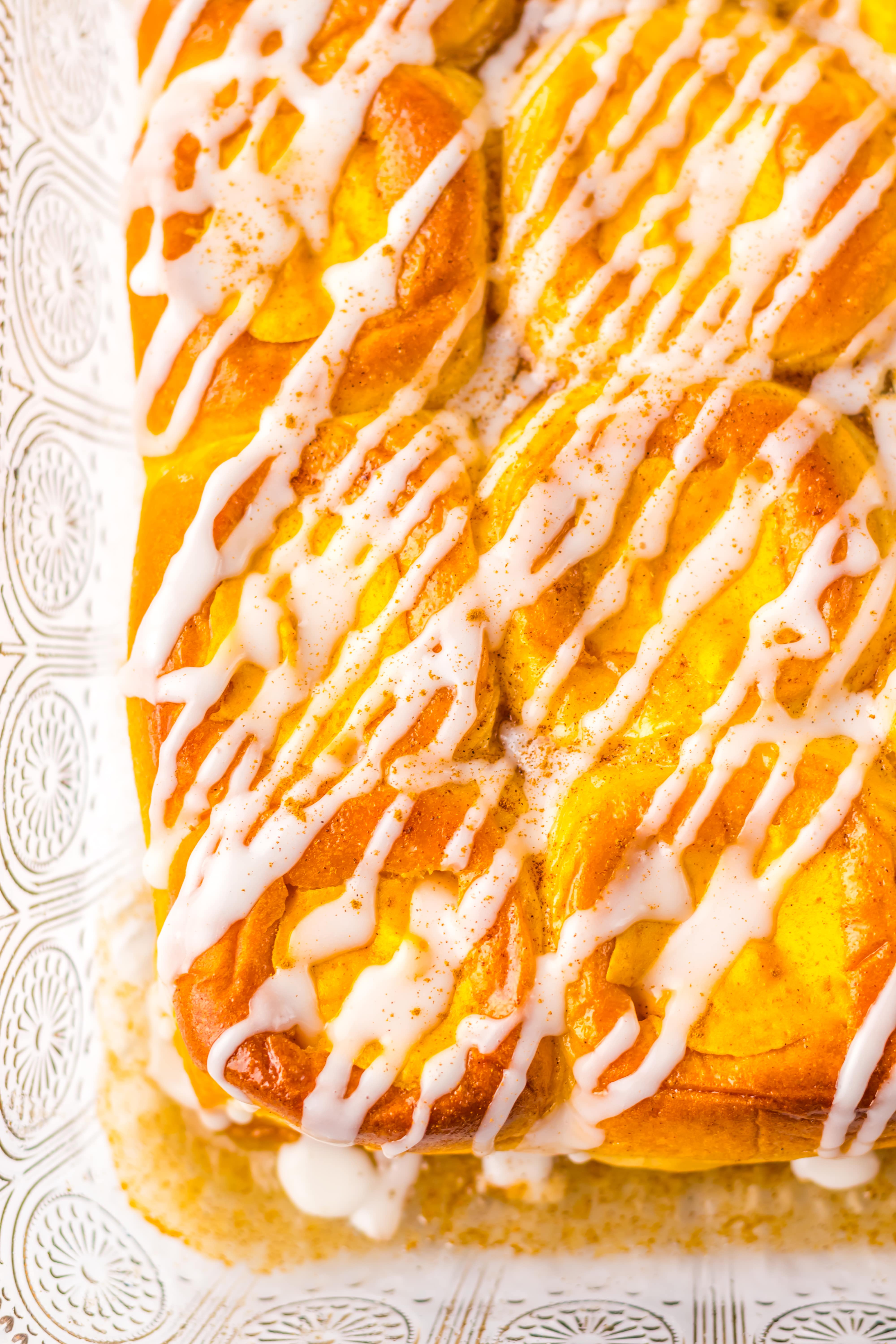 a closeup of pumpkin danish hawaiian rolls drizzle with white glaze