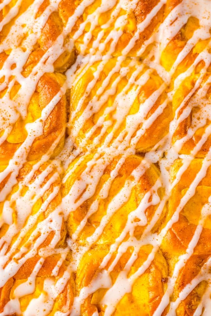 a closeup of pumpkin danish hawaiian rolls drizzle with white glaze