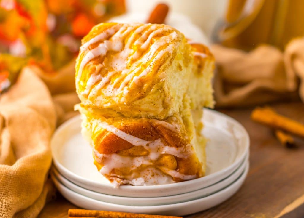 two pumpkin danish hawaiian rolls stacked on a small white dessert plate