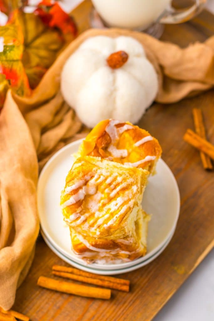 two pumpkin danish hawaiian rolls stacked on a small white dessert plate