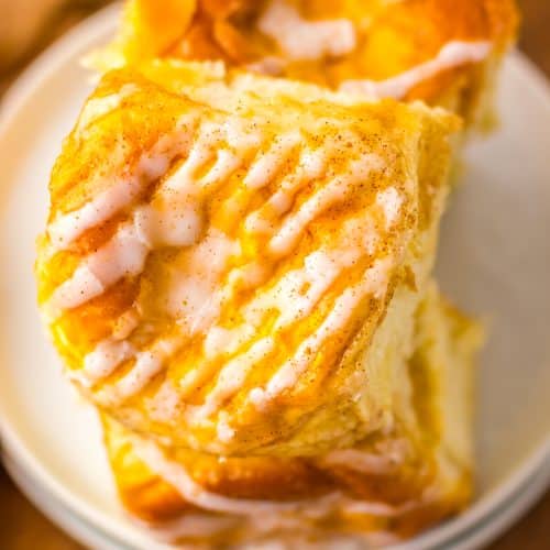 two pumpkin danish hawaiian rolls stacked on a small white dessert plate