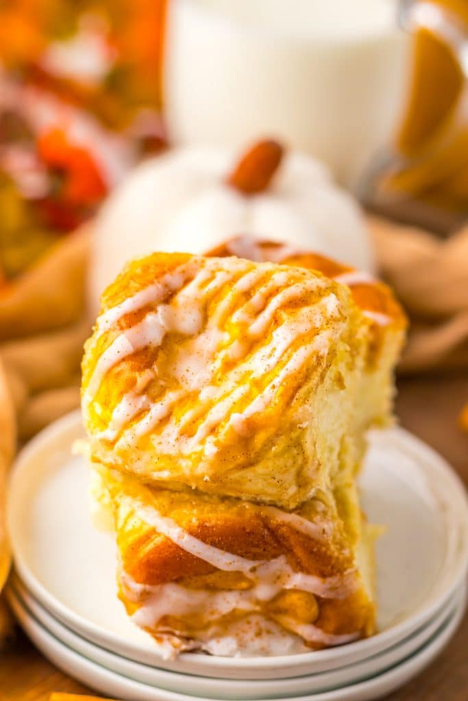 two pumpkin danish hawaiian rolls stacked on a small white dessert plate