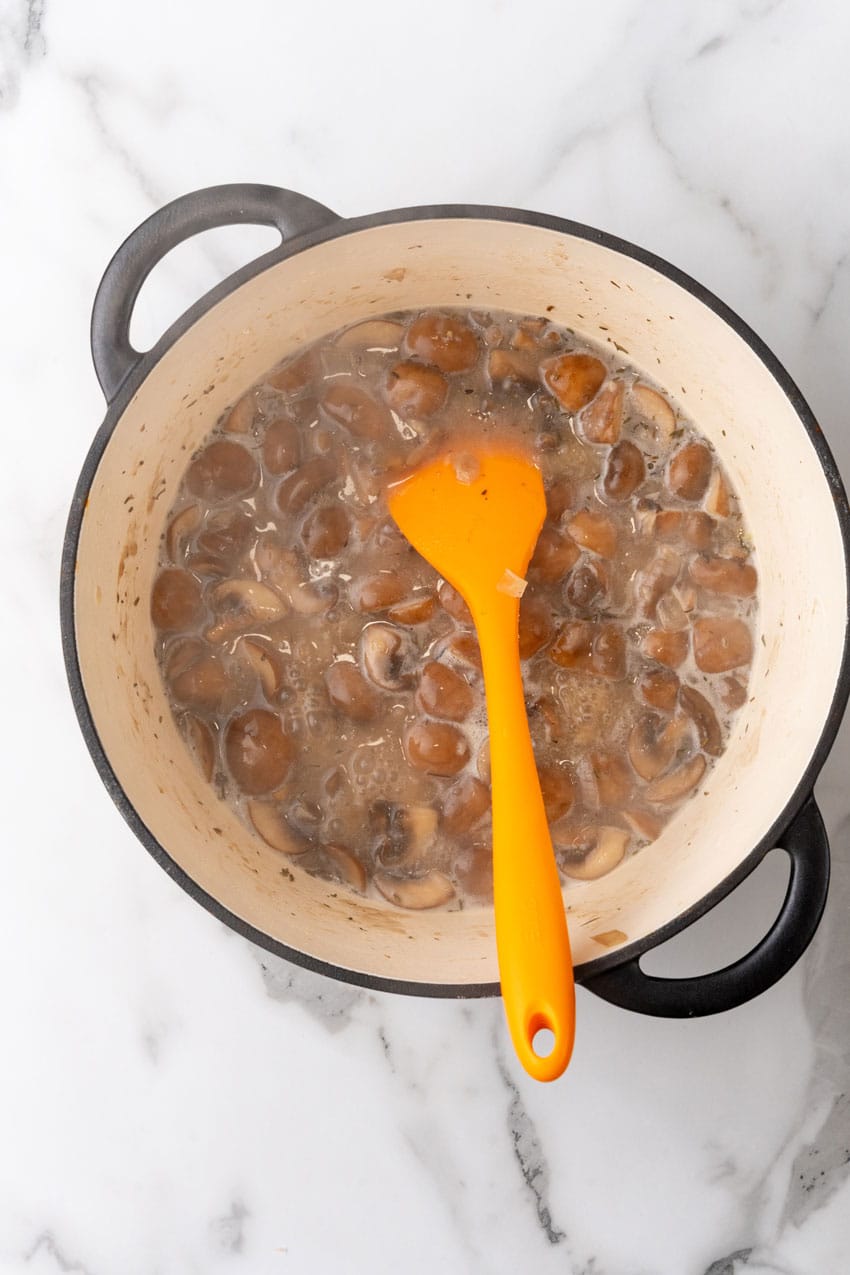 mushrooms and onions sauteeing in butter in a large dutch oven