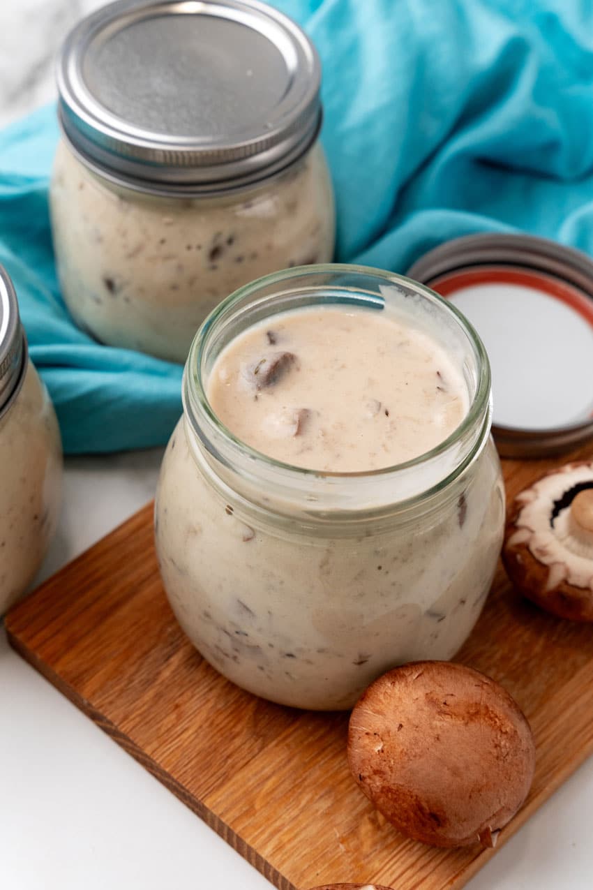 homemade cream of mushroom soup in a glass jar on a wooden cutting board