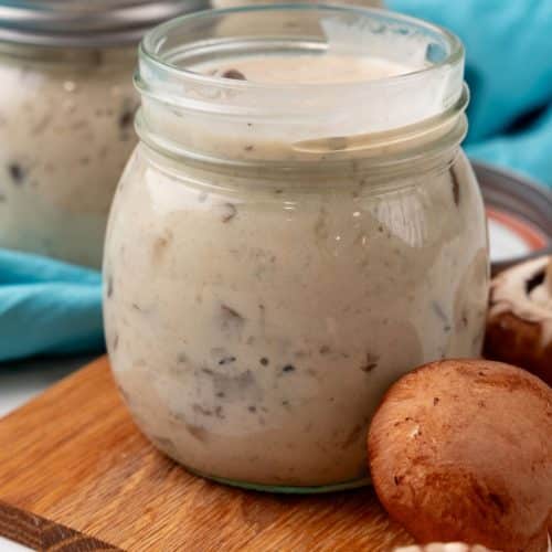 homemade cream of mushroom soup in a glass jar on a wooden cutting board