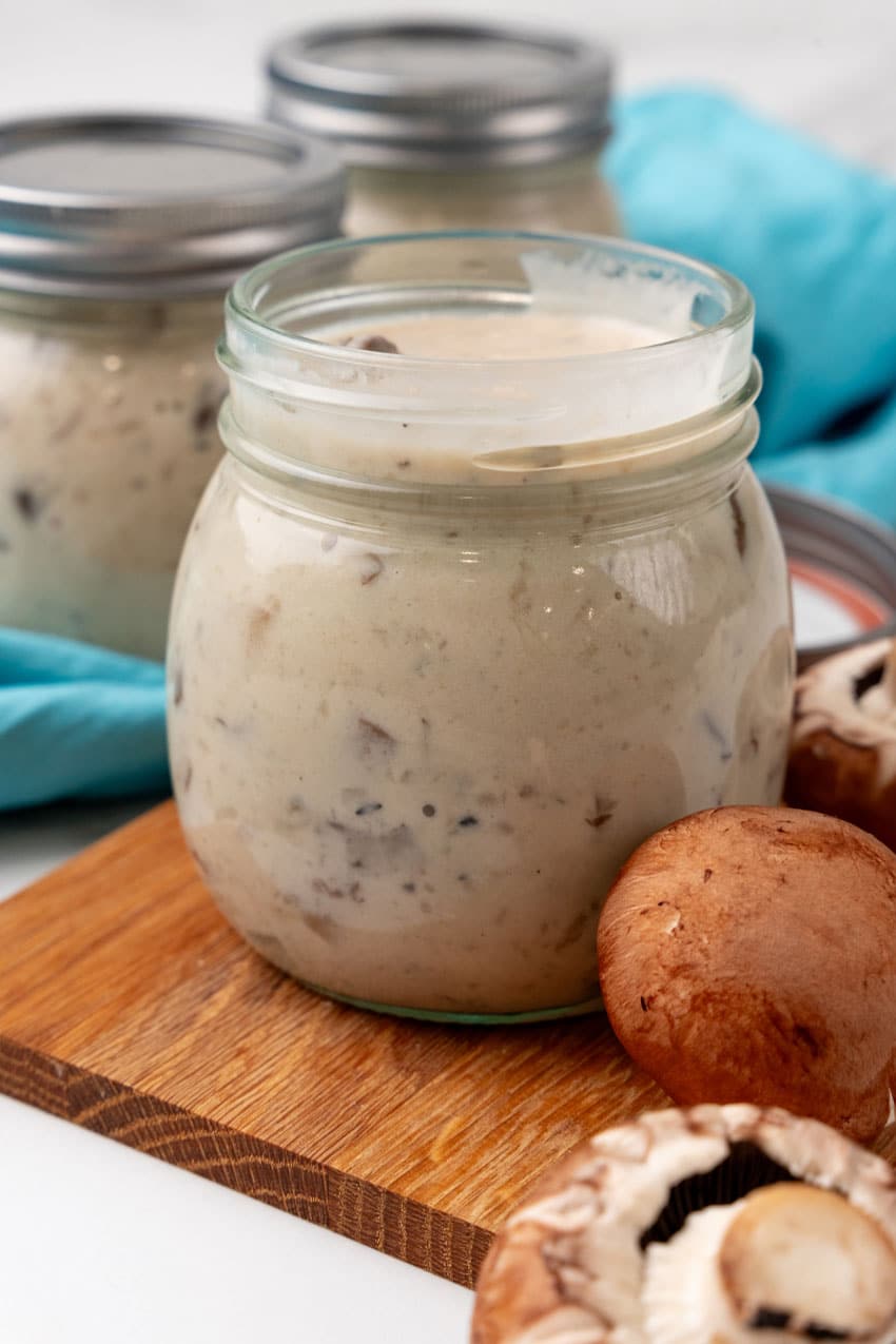 homemade cream of mushroom soup in a glass jar on a wooden cutting board