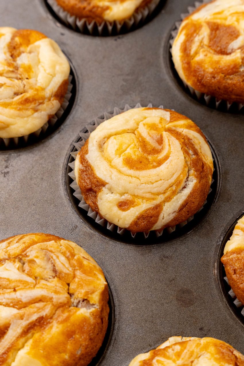 baked pumpkin cream cheese swirl muffins in a metal muffin pan