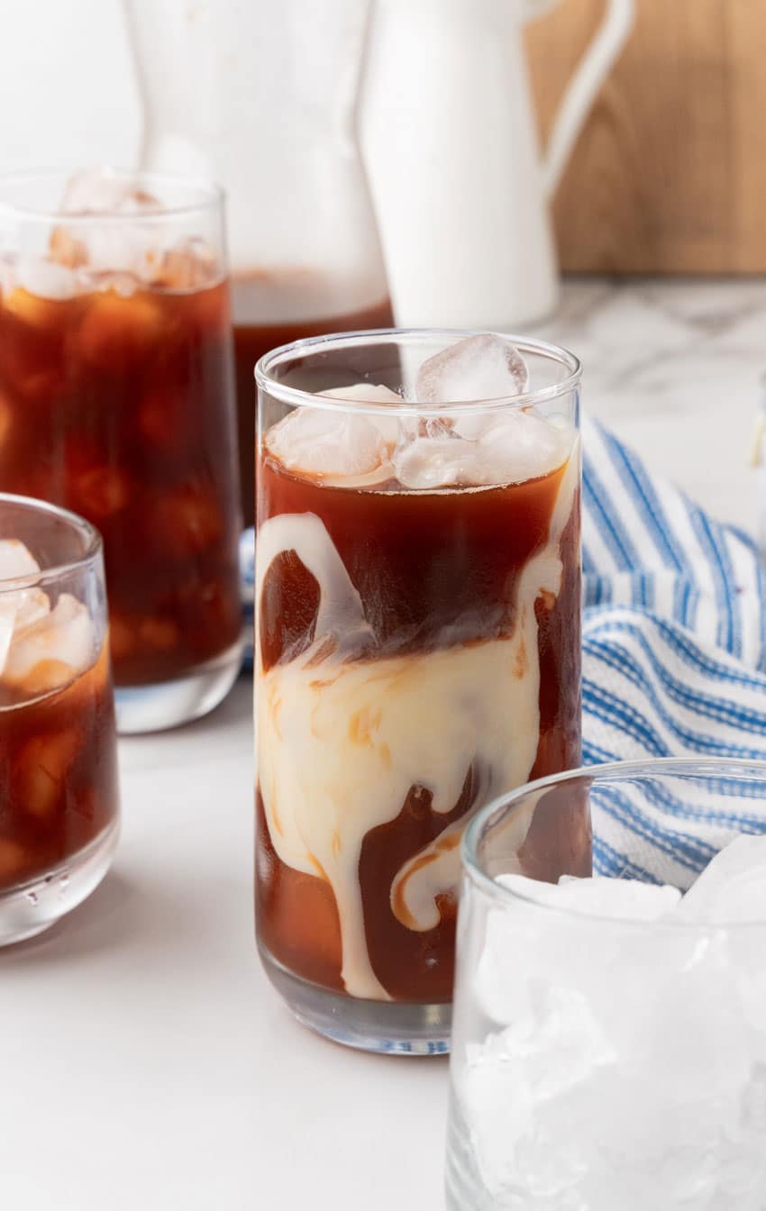 thai tea over ice cubes in a tall clear glass