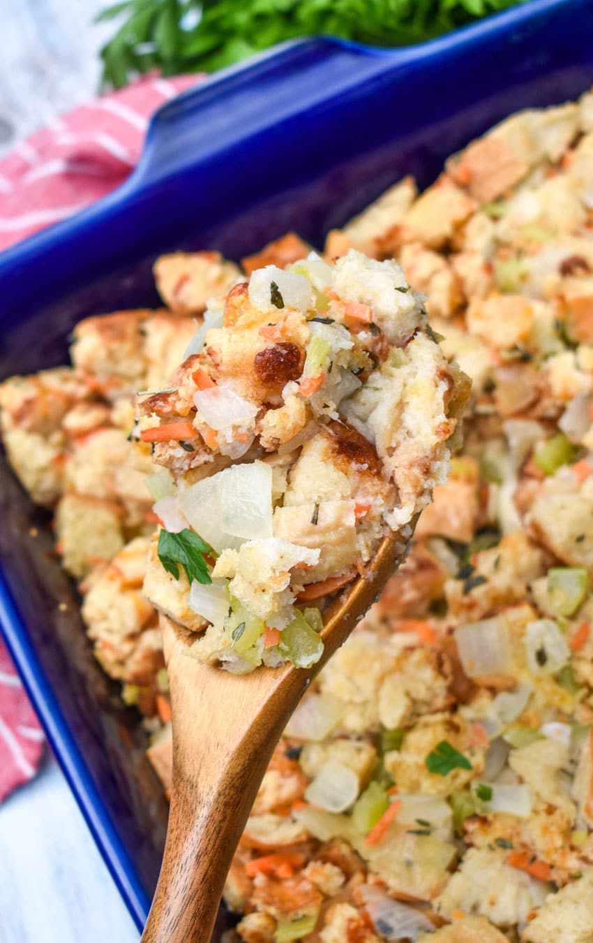 a wooden spoon holding up a scoop of cheddar bay biscuit stuffing