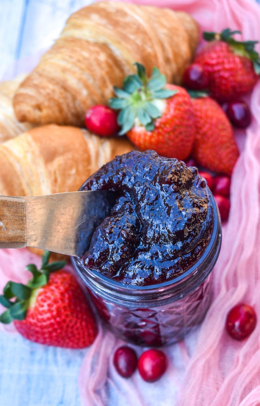 a wooden handled spreader sticking out a jar of homemade christmas jam