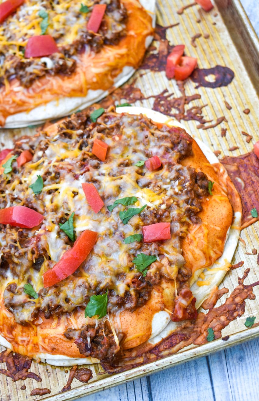 two mexican pizzas with extra meat on a metal baking sheet