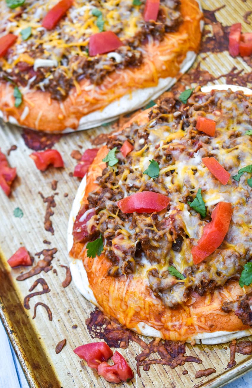 two mexican pizzas with extra meat on a metal baking sheet