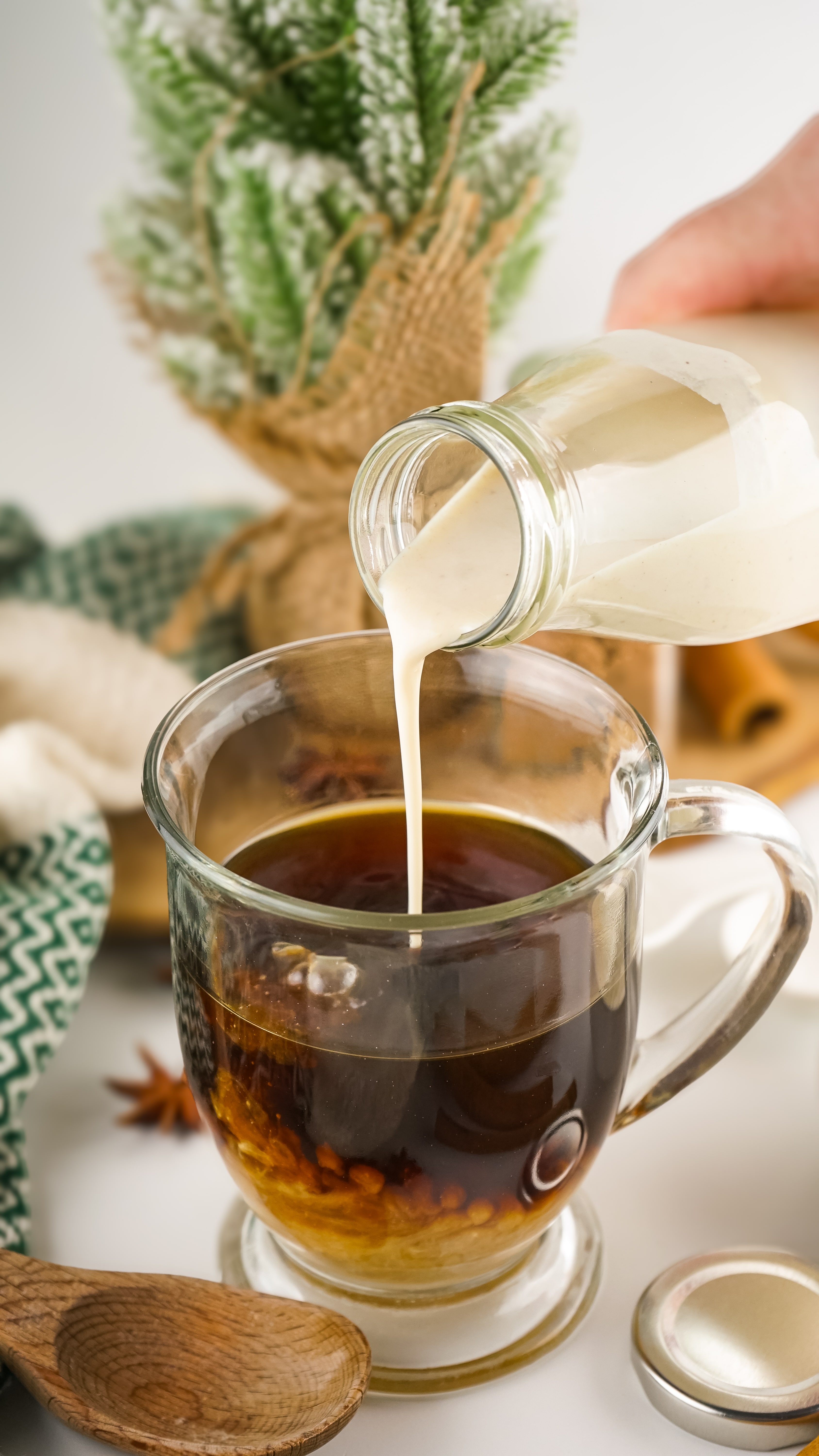 eggnog coffee creamer being poured into a glass mug filled with black coffee