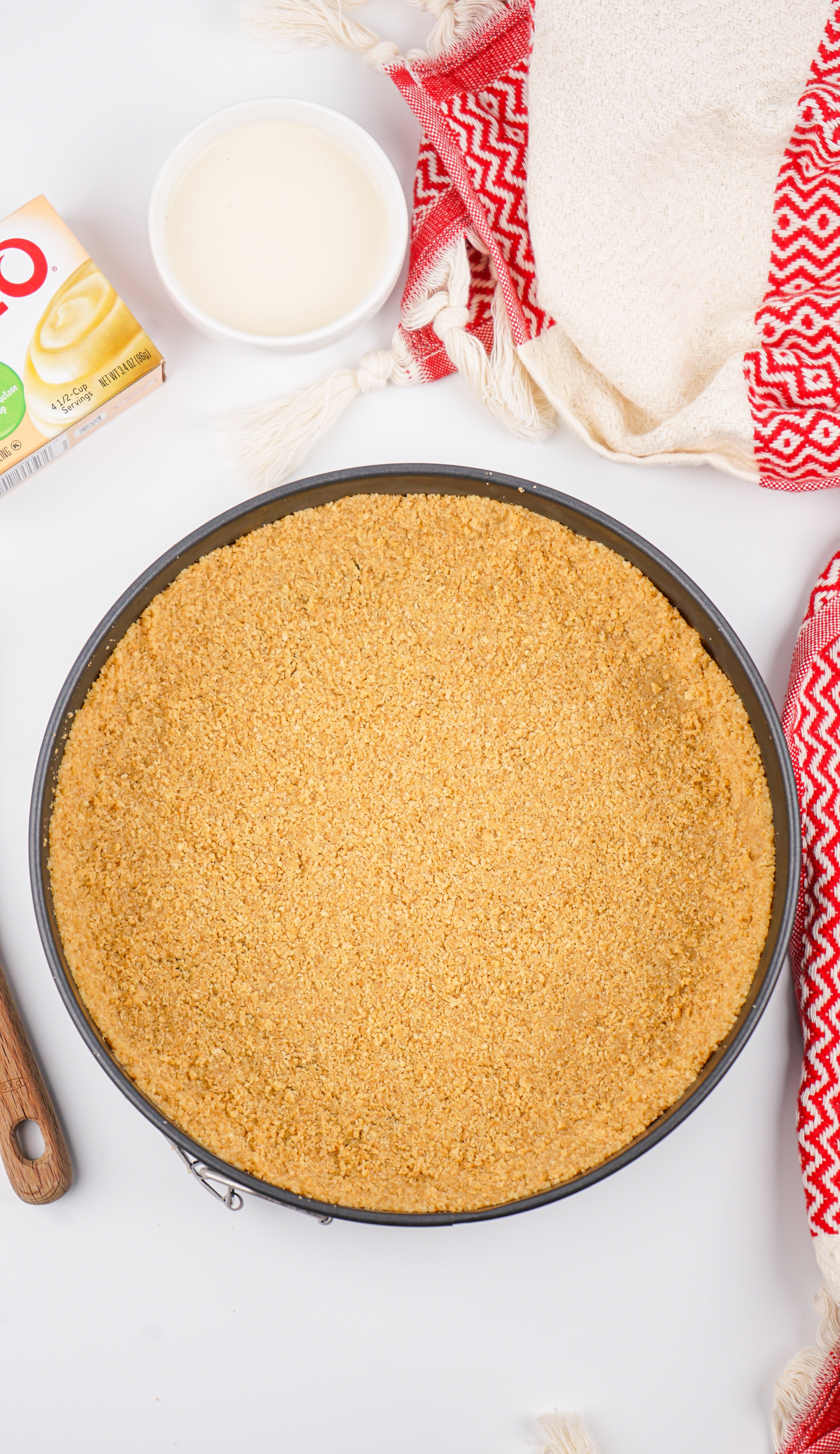 graham cracker pie crust spread out in a metal spring form pan