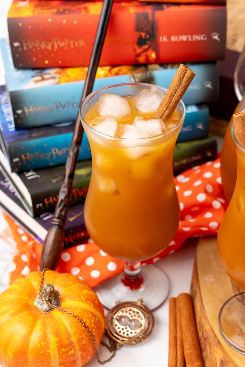 harry potter pumpkin juice in two glasses with ice cubes and cinnamon sticks as a garnish