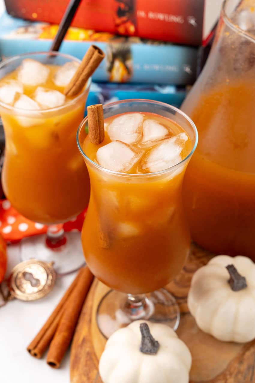 harry potter pumpkin juice in two glasses with ice cubes and cinnamon sticks as a garnish