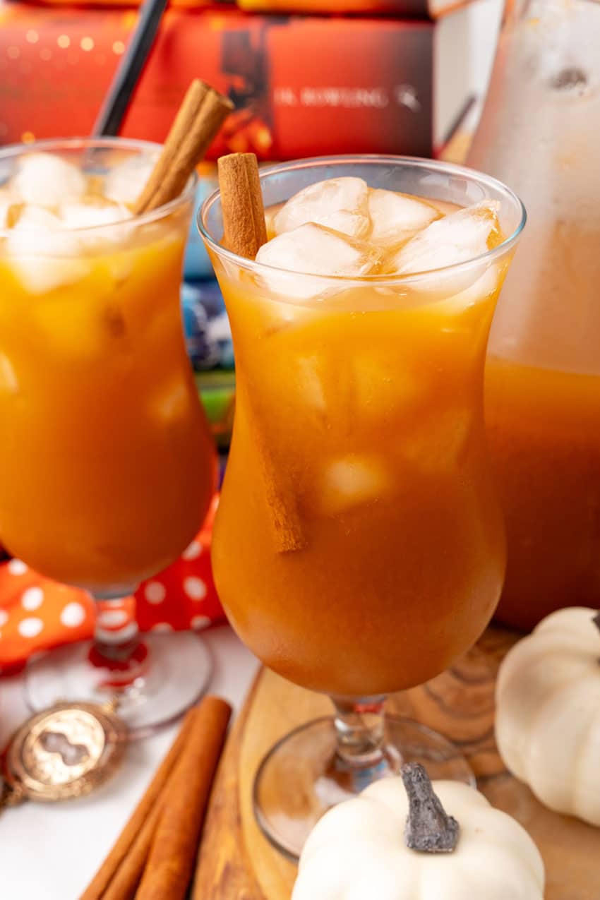 harry potter pumpkin juice in two glasses with ice cubes and cinnamon sticks as a garnish