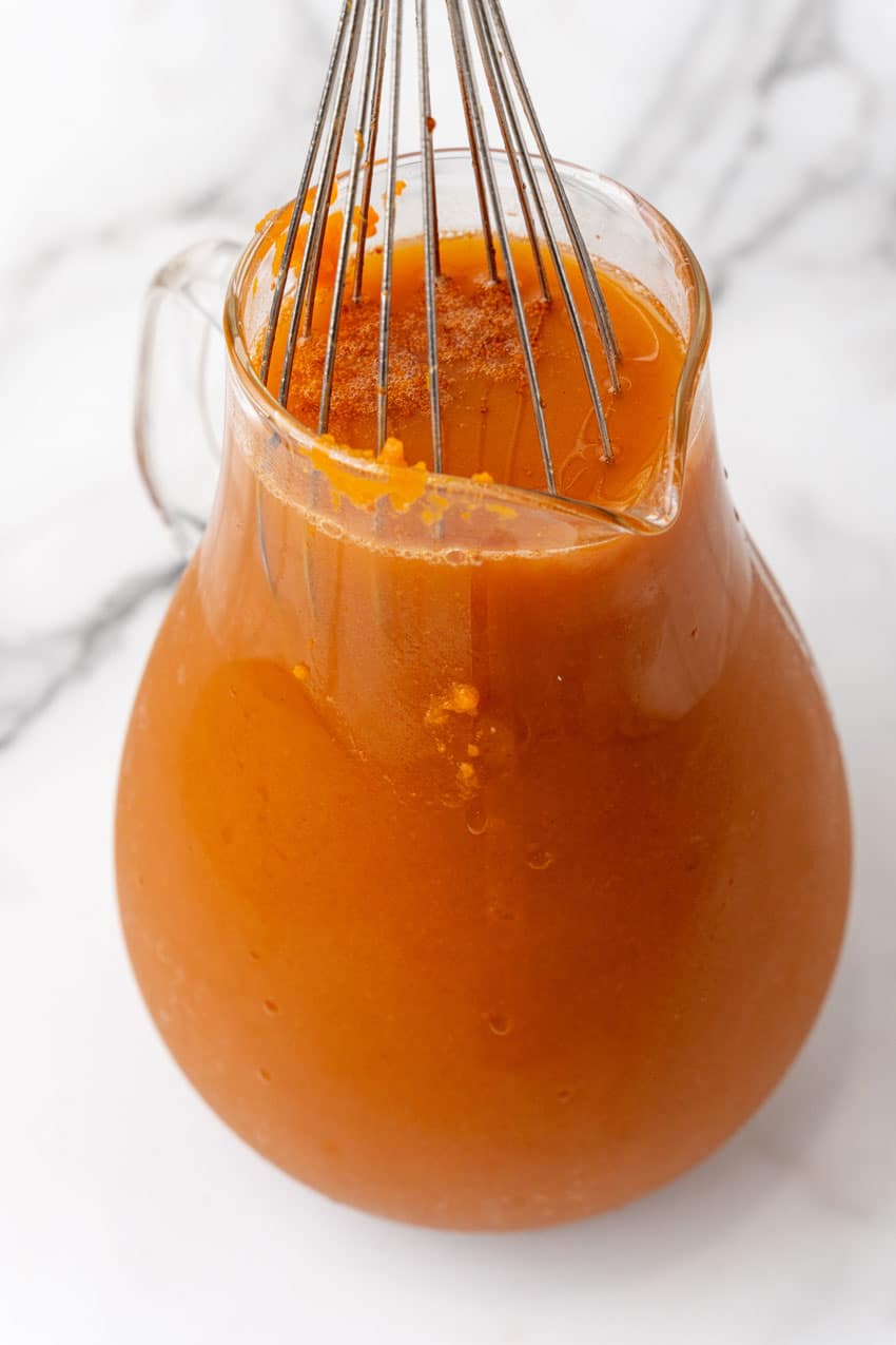 pumpkin juice ingredients being whisked together in a small glass pitcher