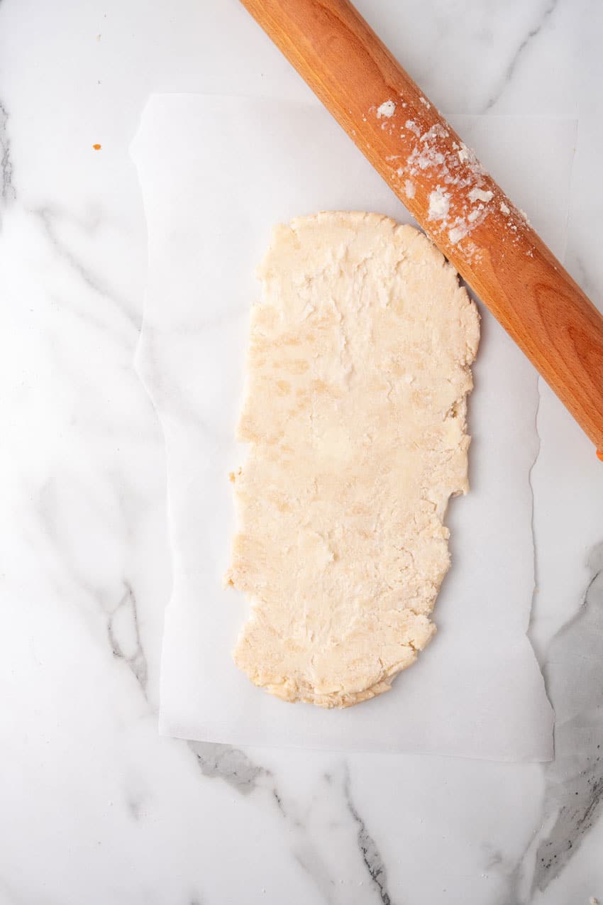 rolled out puff pastry dough next to a floured wooden rolling pin