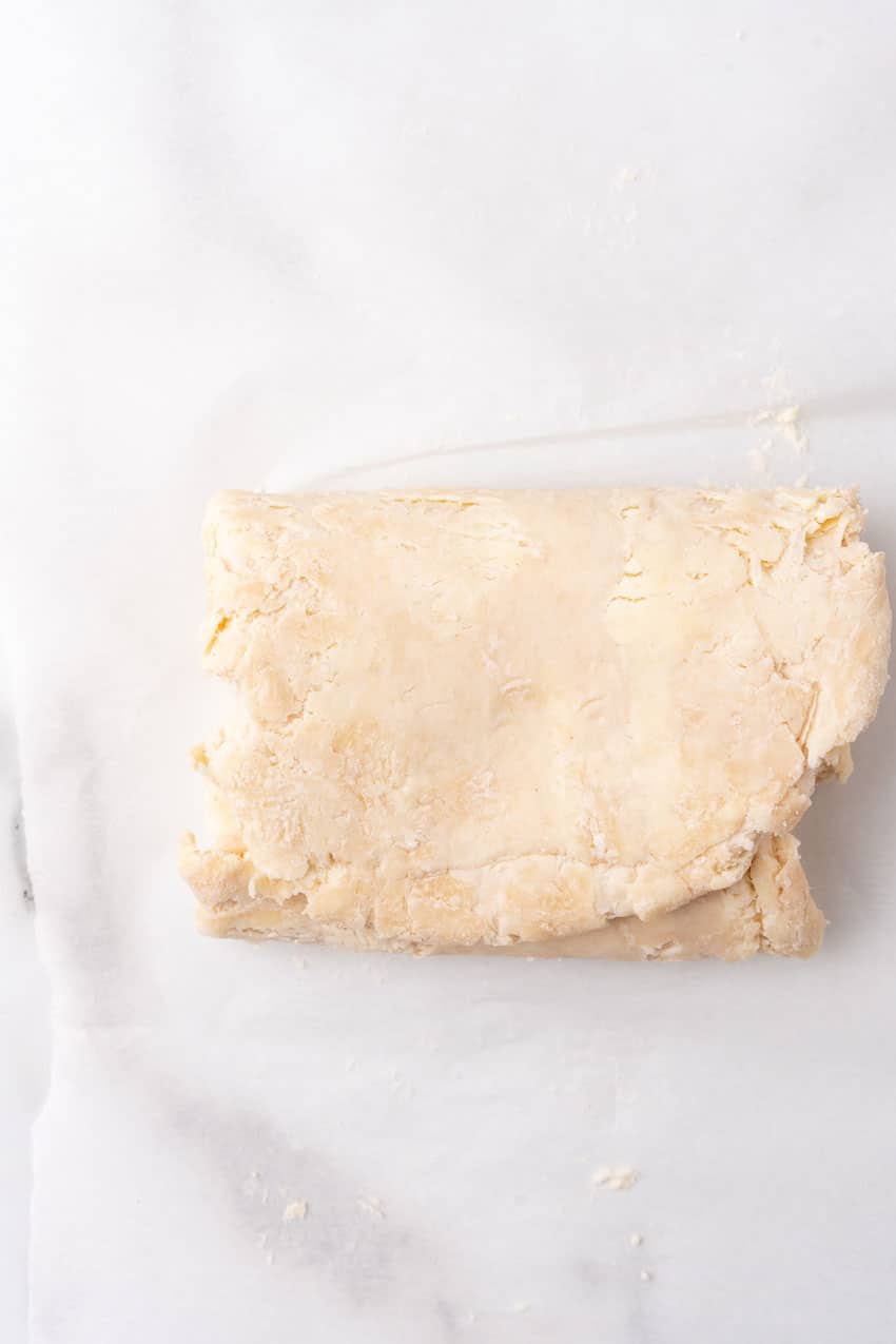 folded sheet of homemade puff pastry dough on a floured piece of parchment paper