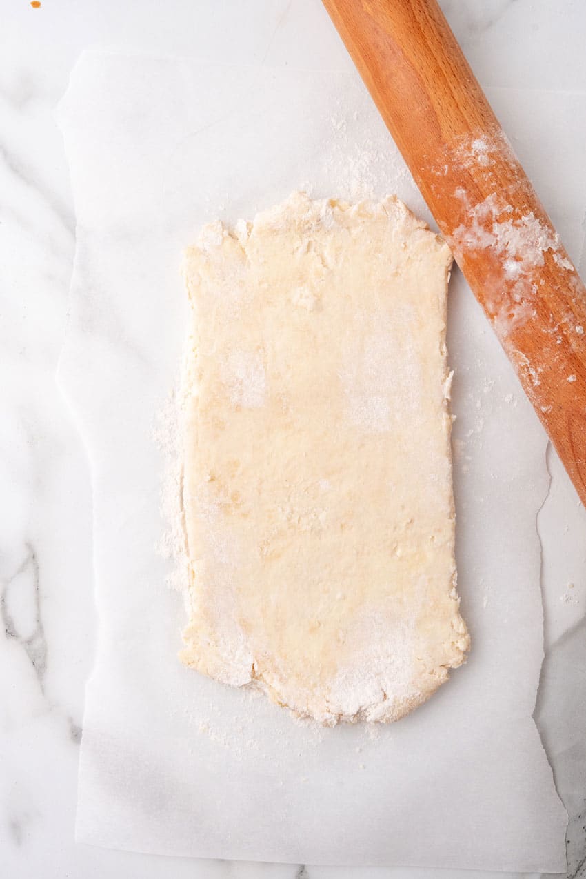 rolled out puff pastry dough next to a floured wooden rolling pin