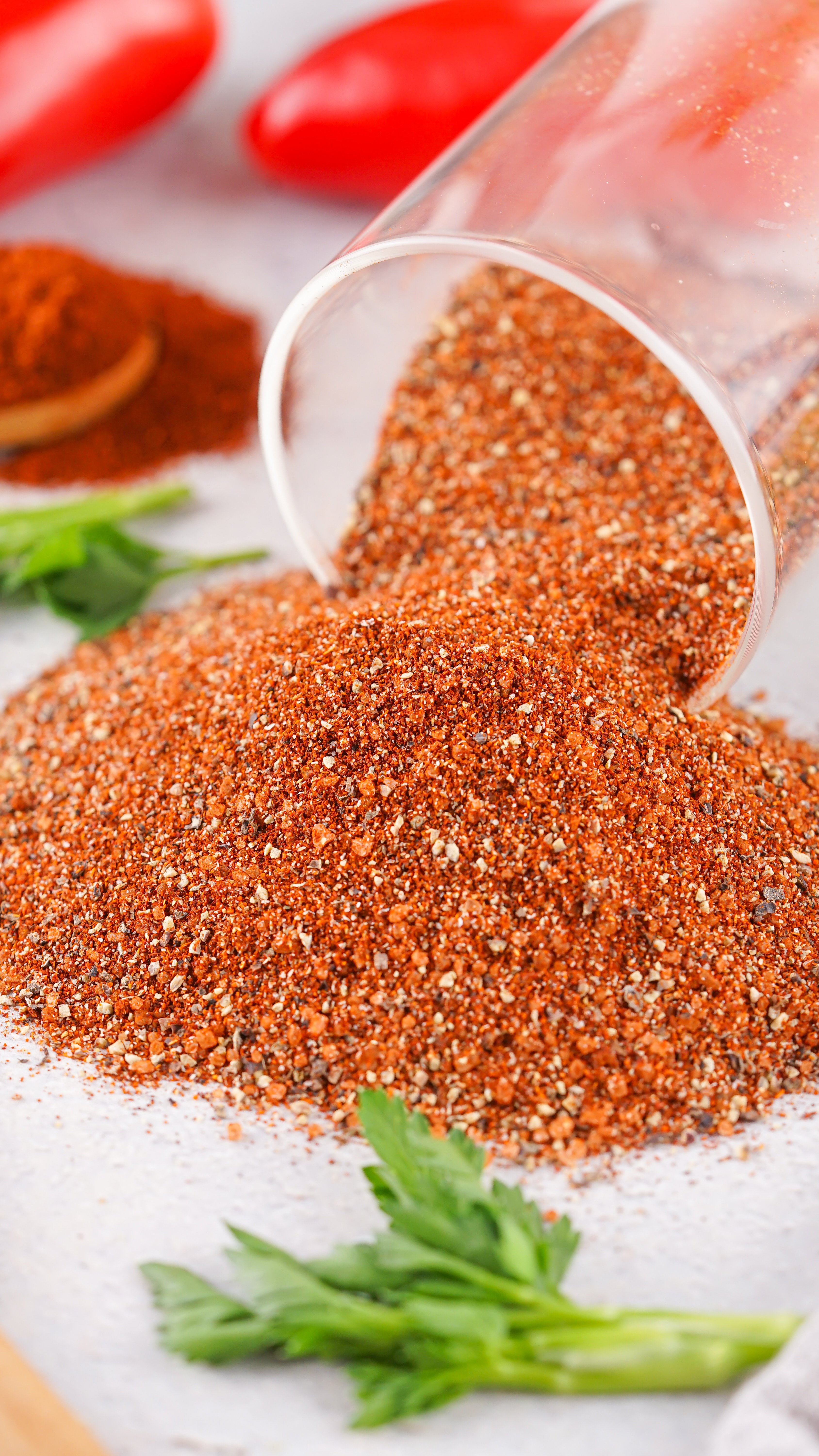 homemade barbecue rub spilling out of a glass jar onto a white kitchen counter