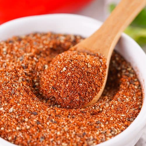 a wooden spoon scooping homemade barbecue rub out of a small white prep bowl