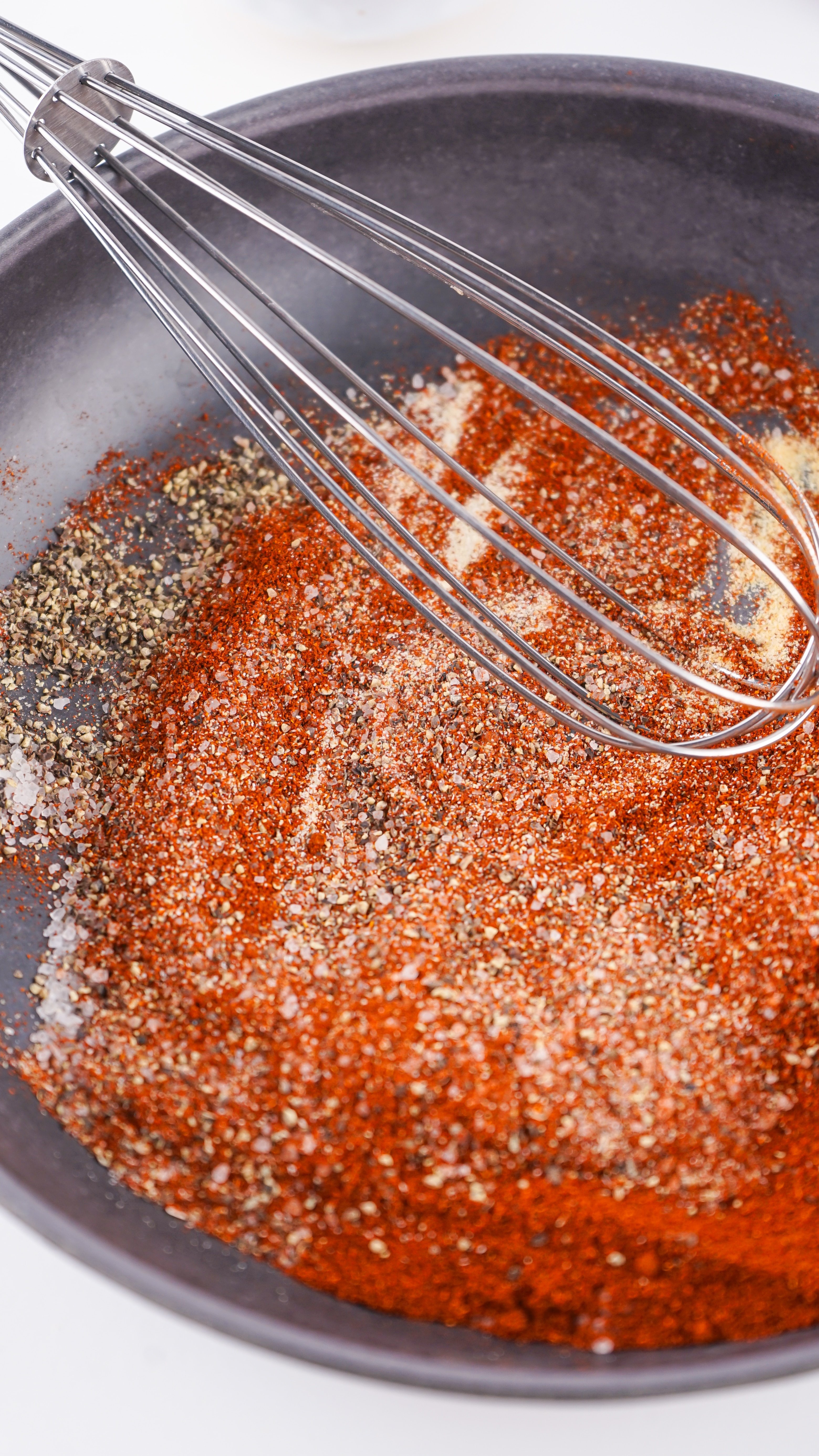 spices being whisked together in a shallow black bowl